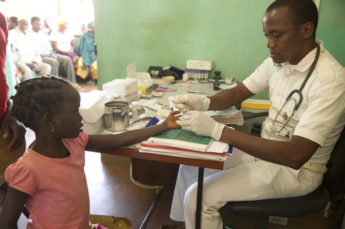 Pfleger testet Kind auf Malaria. Mosambik.